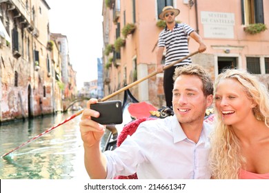 Travel Couple In Venice On Gondole Ride Romance In Boat Happy On Vacation Holidays. Romantic Young Beautiful Couple Taking Selfie Photo With Smartphone Sailing In Venetian Canal In Gondola. Italy.