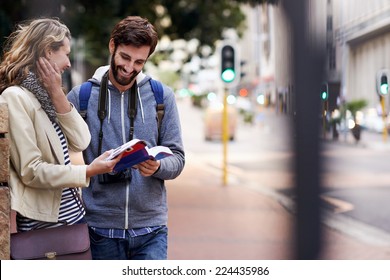 Travel Couple Walking Around City On Vacation With Guide Book Having Fun