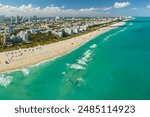 Travel destination in United States. South Beach sandy surface with tourists relaxing on hot Florida sun. Tourism infrastructure in southern USA. Miami Beach city with high luxury hotels and condos