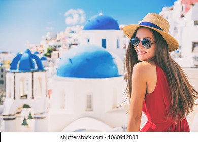 Travel Europe summer holiday girl enjoying Oia, Santorini Greece cruise vacation. Sun getaway Asian woman smiling in hat and sunglasses.