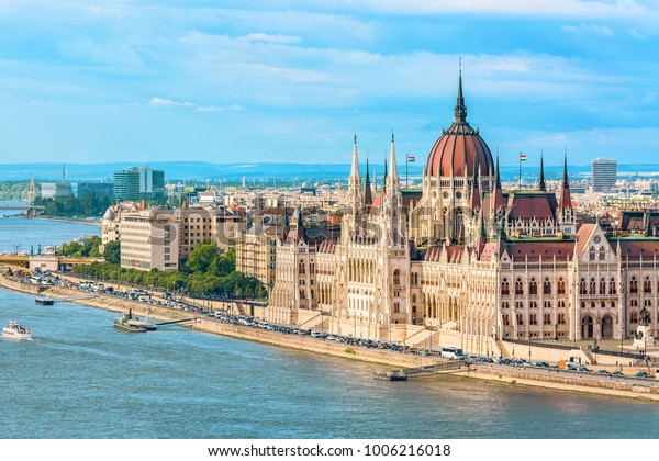 Travel and european tourism concept. Parliament\
and riverside in Budapest Hungary with sightseeing ships during\
summer day with blue sky and\
clouds