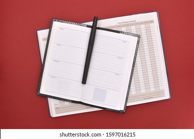 Travel Expense Report Book Under Open Datebook With Black Felt Tip Pen Red Background