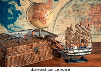 Travel and explore the world concept. Discover the world in old style. Close up on a globe map next to a old ship model, old airplane model, luggage and binoculars. World map in background.