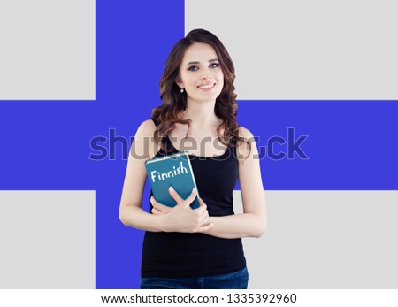 Travel in Finland and learn finnish language. Happy smiling woman holding phrasebook against the Finnish flag background