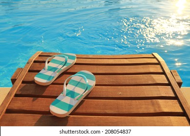 Travel Flip Flops On Wooden Sunbed On Pool