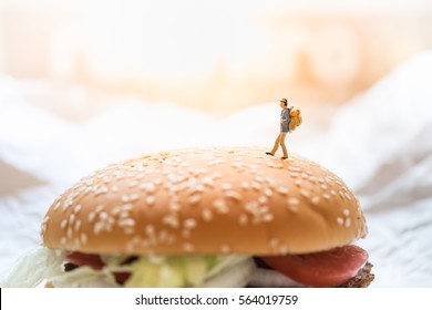 Travel And Food Concept. Traveler Miniature Figure Toy Walking On Top Of Beef Burger.