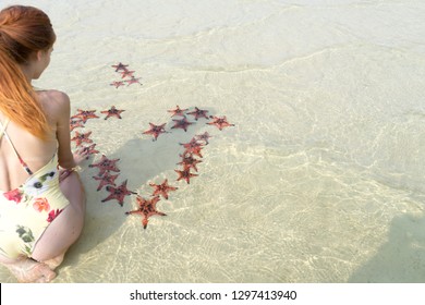 Travel girl in bikini with starfishes,making a heart for Valentines Day in honeymoon in Phu Quoc island with clear water and white sand beach