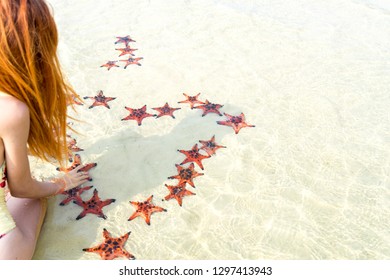 Travel girl in bikini with starfishes,making a heart for Valentines Day in honeymoon in Phu Quoc island with clear water and white sand beach