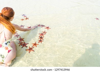 Travel girl in bikini with starfishes,making a heart for Valentines Day in honeymoon in Phu Quoc island with clear water and white sand beach