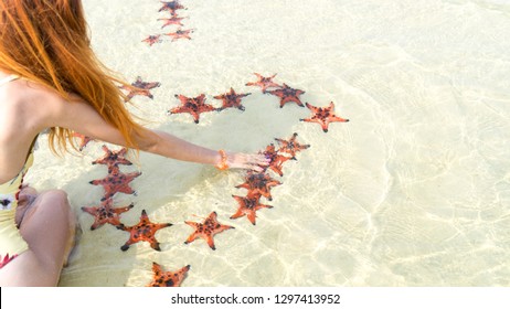 Travel girl in bikini with starfishes,making a heart for Valentines Day in honeymoon in Phu Quoc island with clear water and white sand beach