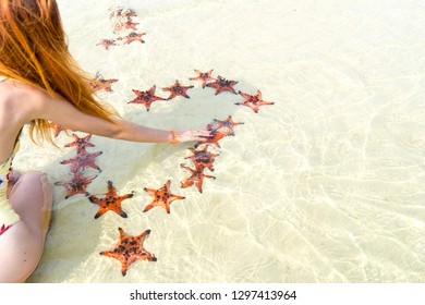 Travel girl in bikini with starfishes,making a heart for Valentines Day in honeymoon in Phu Quoc island with clear water and white sand beach