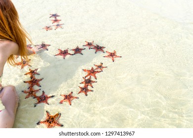 Travel girl in bikini with starfishes,making a heart for Valentines Day in honeymoon in Phu Quoc island with clear water and white sand beach