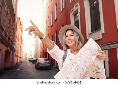 Travel Guide. Young Female Traveler With Backpack And With Map On The Street. Travel Concept