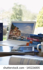 Travel Guides Next To Laptop On Table