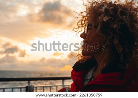 Travel and happiness expression side portrait concept. One woman smiling and enjoying freedom. Traveler tourist young lady with sunset and ocean in background. Ferry cruise boat ship transport. Sun