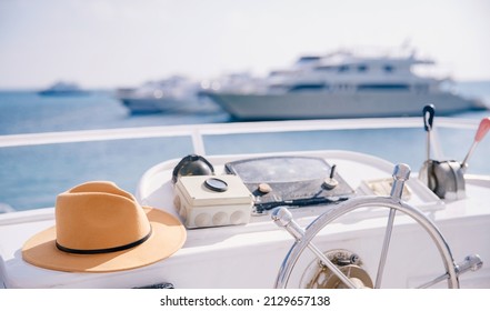 Travel hat lies on steering wheel of modern luxury yacht, concept banner trip on sea, boat rental.