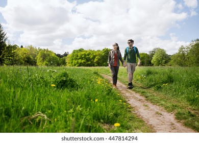 travel, hiking, backpacking, tourism and people concept - happy couple with backpacks holding hands and walking along country road outdoors - Powered by Shutterstock