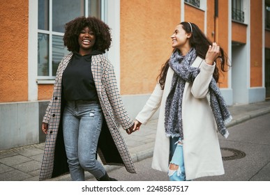 Travel, holding hands and lesbian couple walking in street enjoying holiday, vacation and adventure. Fashion, lgbtq relationship and women dating for happy lifestyle, freedom and relaxing on weekend - Powered by Shutterstock