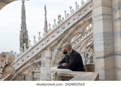 Travel, holidays and winter vacations concept - Cityscape serenity: A beaming tourist man finds peace on the roof of Milan Cathedral, his smile adding warmth to the urban skyline - Powered by Shutterstock