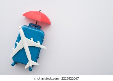 Travel insurance business concept. Red umbrella cover airplane and suitcases on white background. Travel insurance covers loss suitcase, flight delays, cancellations, accident and medical expenses.