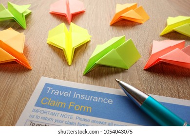 Travel Insurance Claim Form For Filling And Colorful Paper Airplanes On Desk