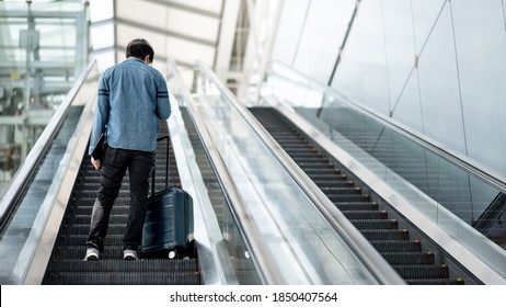 Travel insurance concept. Asian man tourist or passenger man carrying suitcase luggage and digital tablet on escalator in airport terminal. - Powered by Shutterstock