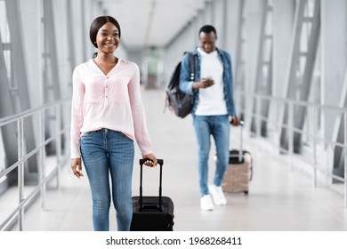 Travel Insurance Concept. Portrait Of Cheerful Black People Walking With Luggages In Airport Terminal, Happy African American Man And Woman Going Down To Plane, Enjoying Upcoming Flight, Free Space