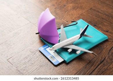 Seguro de viaje. Modelo de avión, pasaporte, paraguas Pequeño y billete en mesa de madera, primer plano. Espacio para texto