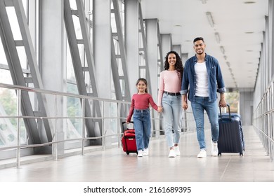 Travel Insurance. Smiling Arabic Family With Daughter Walking With Suitcases At Airport, Happy Middle Eastern Parents And Little Female Child Holding Hands And Looking At Camera, Copy Space