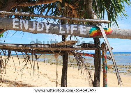 Travel to island Koh Lanta, Thailand. An inscription (Enjoy life) on the wooden abandoned hut on a beach background.