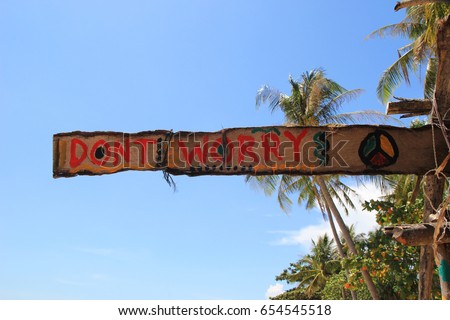 Travel to island Koh Lanta, Thailand. An inscription (Don’t worry) on the wooden abandoned hut on a sky background.