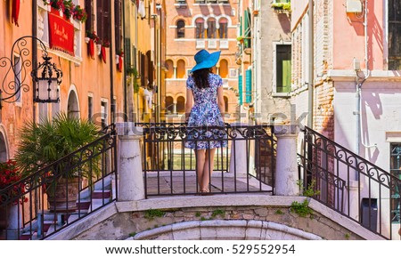 Travel to Italy. Girl standing on the bridge in Venice. Beautiful well-dressed woman posing on a bridge over the canal in Venice, Italy. Europe travel vacation. Woman traveling to Venice.