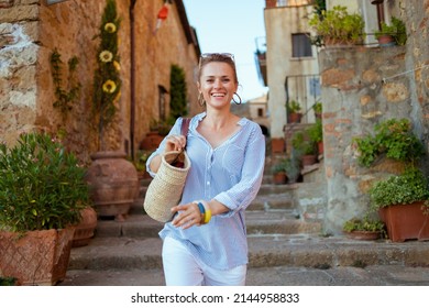 Travel in Italy. happy trendy woman with straw bag having excursion in Pienza in Tuscany, Italy.