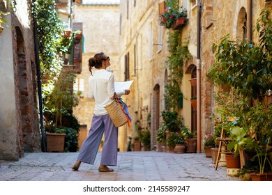 Travel in Italy. Seen from behind stylish woman with map and straw bag enjoying promenade in Tuscany, Italy. - Shutterstock ID 2145589247