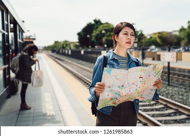 Travel Lady With Holding Paper Map Finding The Direction Waiting For Subway Train Outdoors. Beautiful Tourist Self Guided Trip In San Francisco Commute By Light Rail In The Urban Next The Railway.