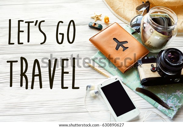 travel. let\'s\
go travel text sign concept . summer travel wanderlust. map camera\
sunglasses passport money phone hat shells car on white wooden\
background top view. hello\
holiday
