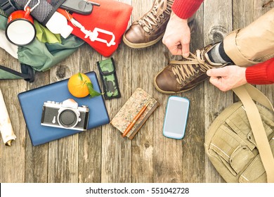 Travel Man Tying Boots For Trekking Day Top View Of Items For Hiking And Adventure - Active Male Hands On Shoelaces Above Angle With Camera Mobile Phone And Backpack On Old Wooden Floor Background