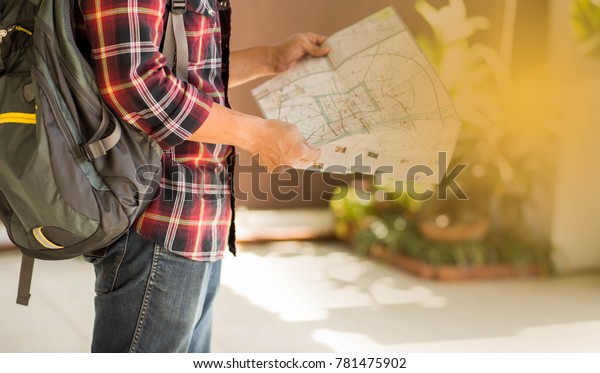 Travel men carrying handbag map in hand. The focus\
of shirt pattern and\
bag.