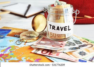 Travel Money Savings In A Glass Jar With Compass, Map And Hat