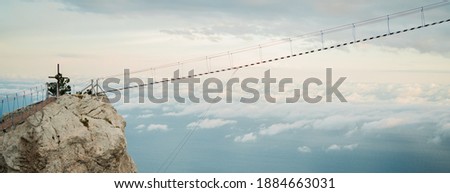 travel in the mountains, dangerous suspension bridge cable car between two rocks. Beautiful background view of the sea and blue sky, panorama, copy space
