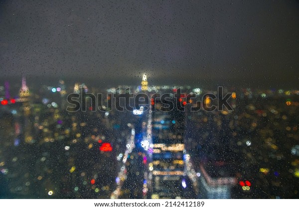 Travel to New York. Manhattan from above viewed\
through a window with rain drops on it and blurry out of focus\
background. Inspirational mood\
photo.