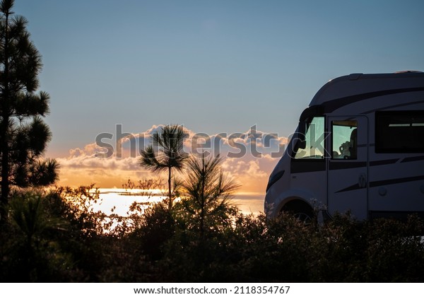 Travel people\
lifestyle and nomadic life with white camper van motorhome and\
beautiful colorful sunset on the ocean in background. Travel and\
enjoy freedom and nature with\
rv