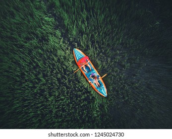 Travel. People Sail In Boat On Lake With Grass Aerial View, Rowing On Canoe At Overgrown River