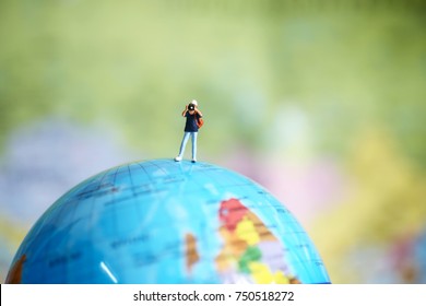 Travel and photograph concept. Traveler miniature figure with camera stand and take a photo of mini globe ball on white background - Powered by Shutterstock