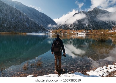 Travel photographer man with backpack at mountain lake Issyk, Almaty, Kazakhstan