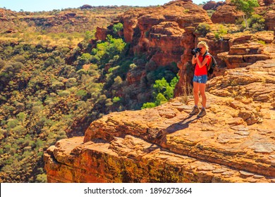 Travel photographer taking pictures of sandstone cliff in Kings Canyon Watarrka National Park. Central Australia travel discovery concept. Woman with professional camera in Northern Territory, Outback