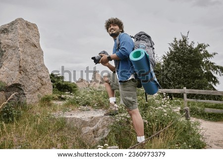 travel and photography concept, happy indian backpacker using digital camera during nature trip