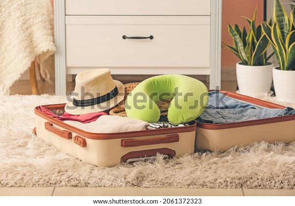 Travel pillow\
and open suitcase on floor in\
room