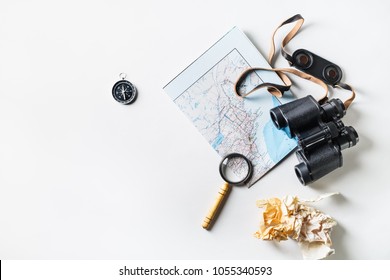 Travel Plan Background. Map, Binoculars, Compass, Magnifier And Crumpled Paper On White Paper Background. Flat Lay.