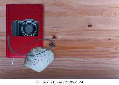 Travel planning. Camera, notepad and seashell on wooden table